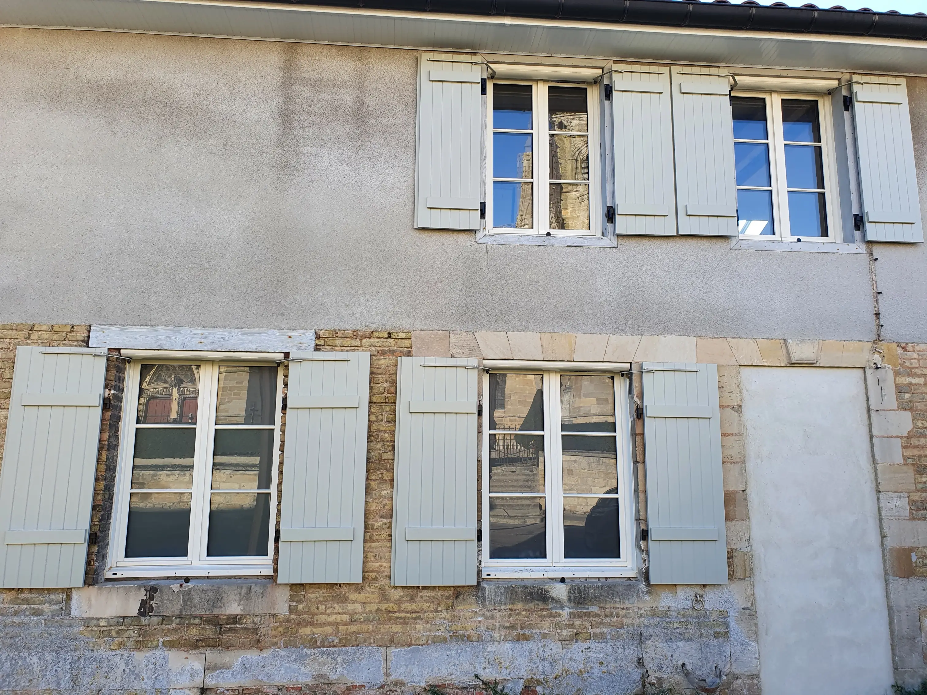 Volets roulants gris sur façade en pierre